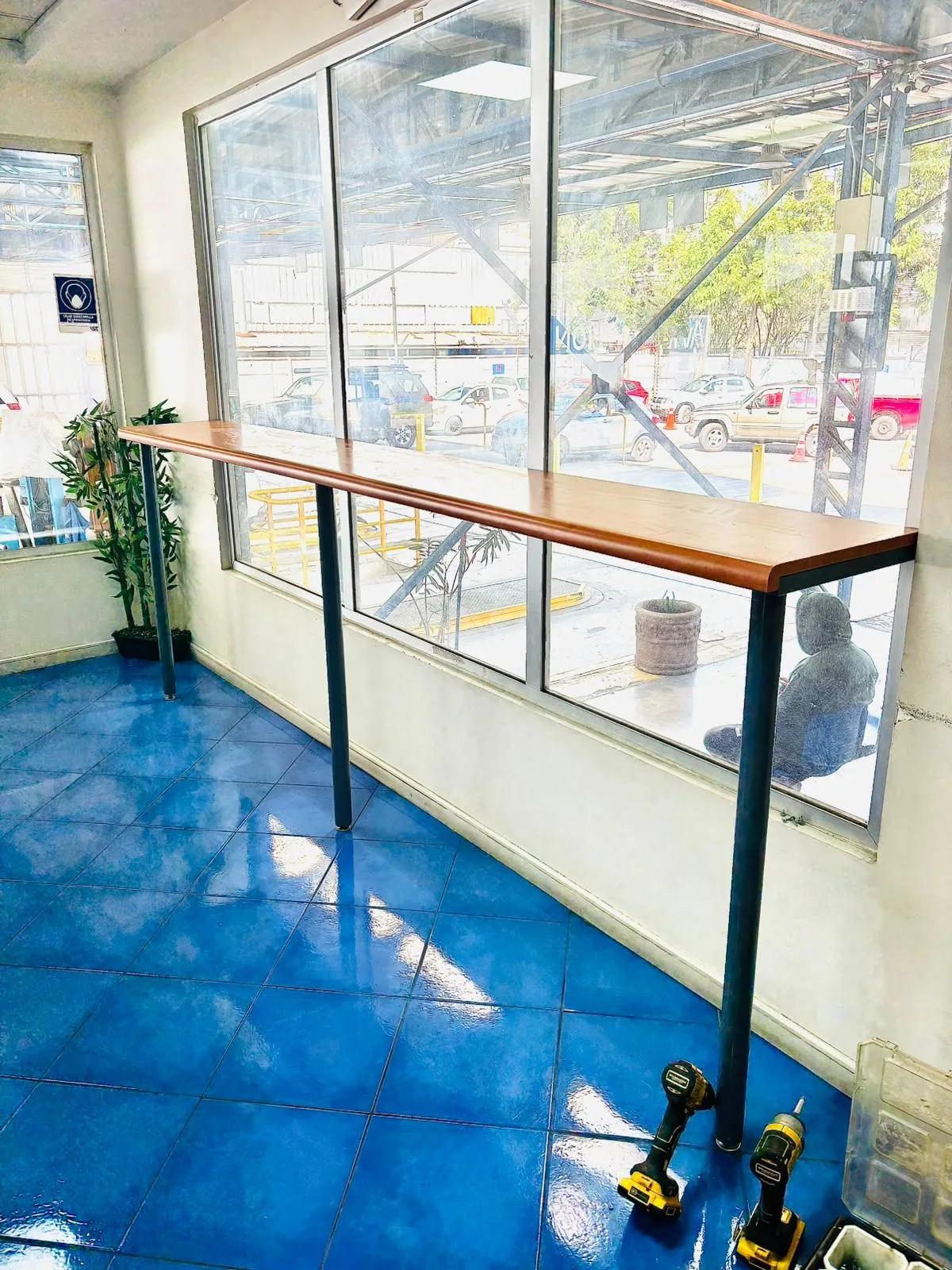 Mesa larga de madera sobre estructura metálica junto a un ventanal.